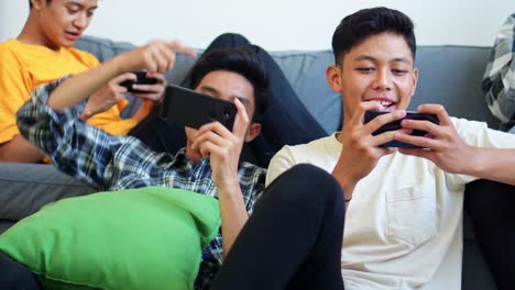 friends enjoy gaming session at home and focused on their smartphones, highlighting digital leisure