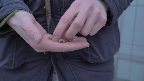 poor white man counting cents he has left on his hand outdoors