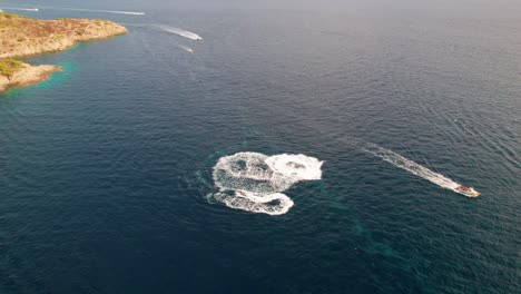 drone towards jet skis circling in sea off coastline of cap de creus