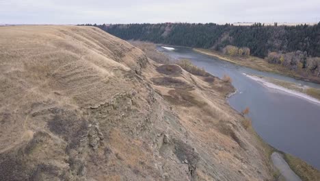 aerial: low eroded cliffs embank dry river valley hillside in autumn