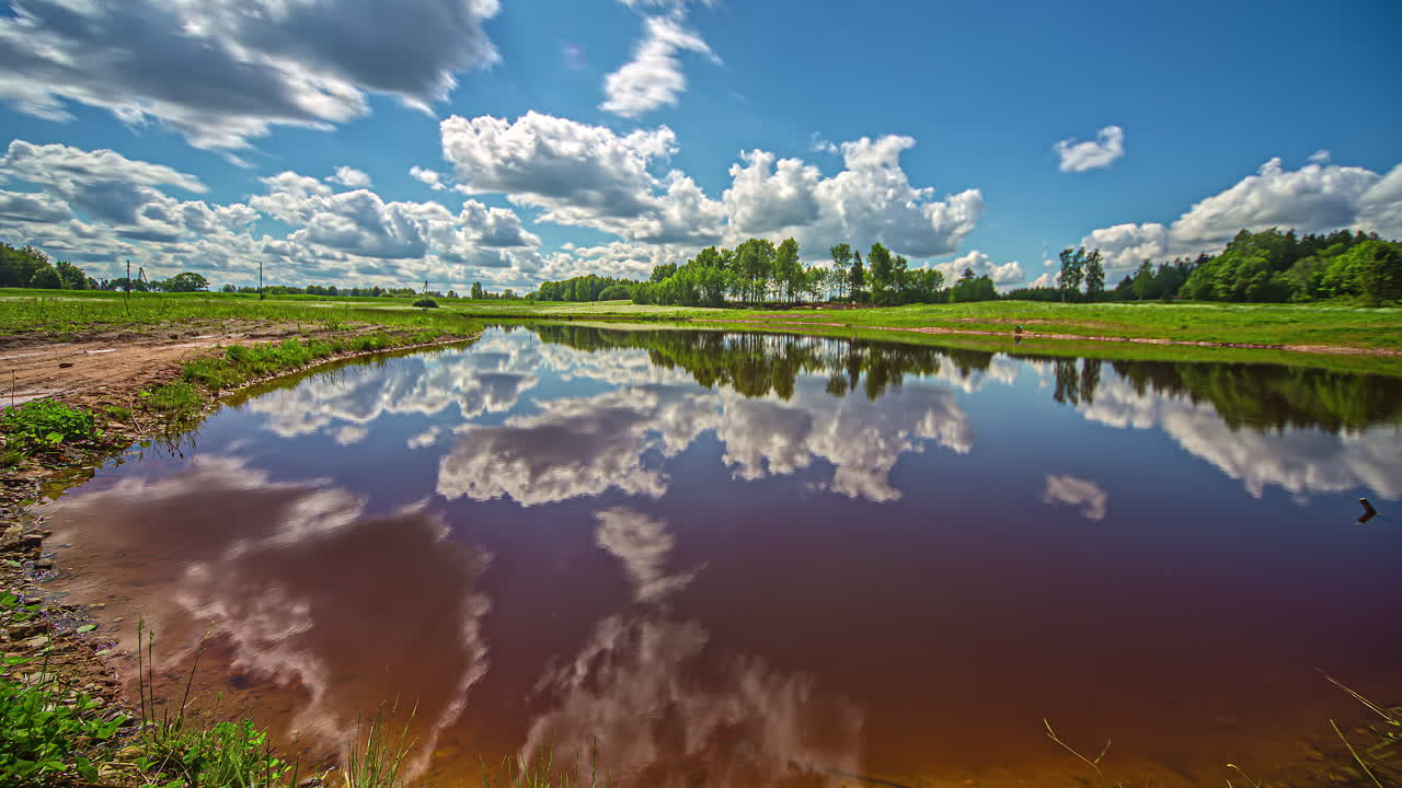 las formaciones de nubes blancas y su movimiento en un cielo azul se reflejan en el agua de un lago