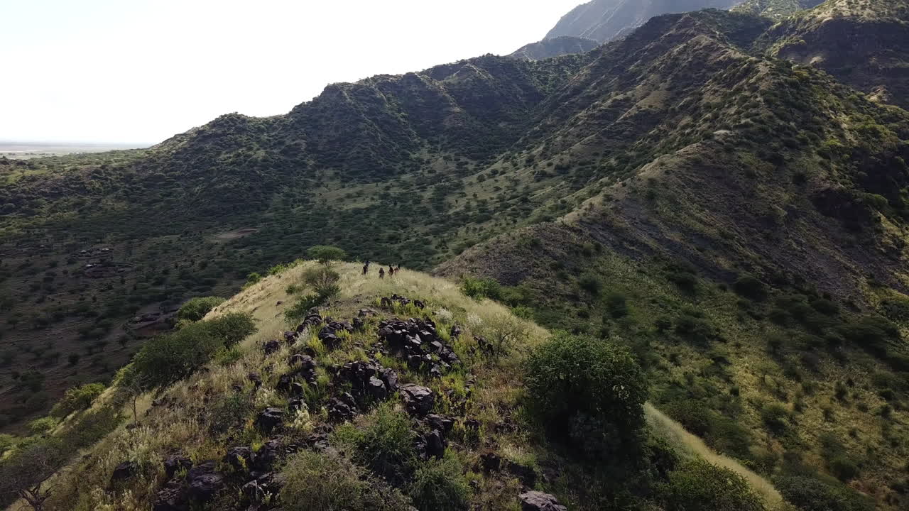 Vista aerea orbitale generale di un gruppo di escursionisti che raggiungono la vetta di una montagna nell'Africa orientale, aiutati da sherpa africani.