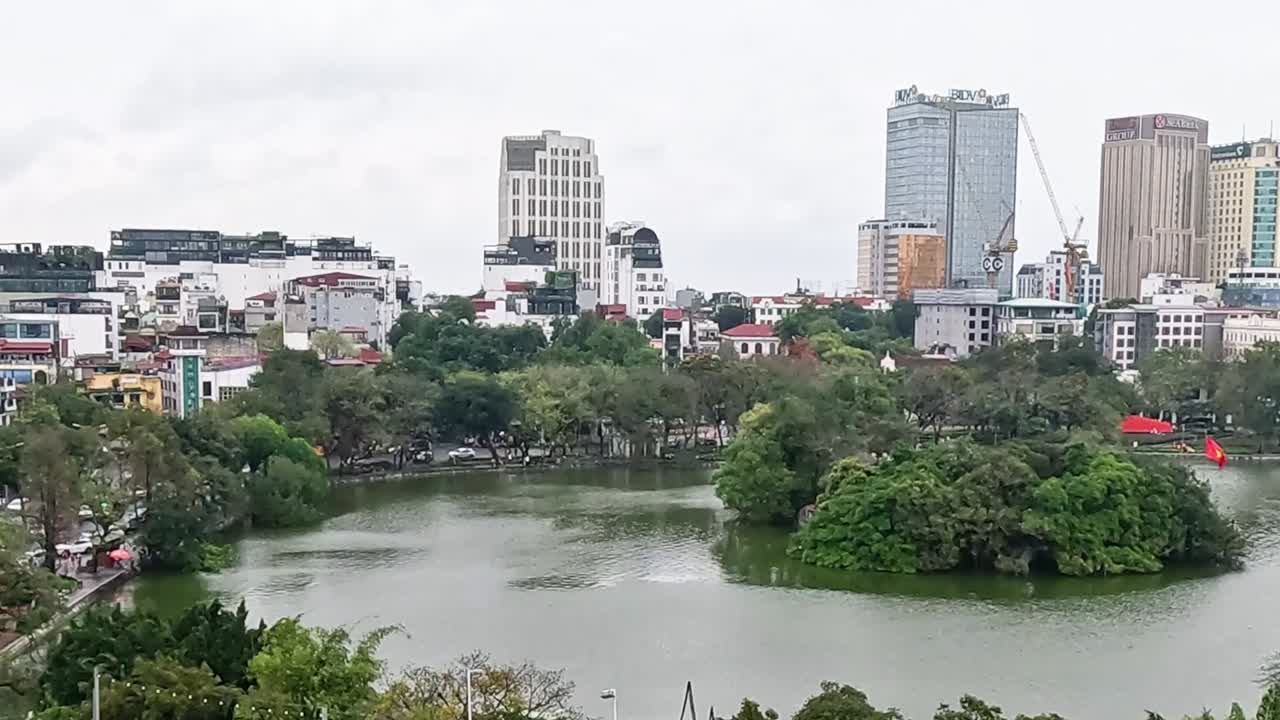 A serene island surrounded by water with a backdrop of urban high-rises and greenery.
