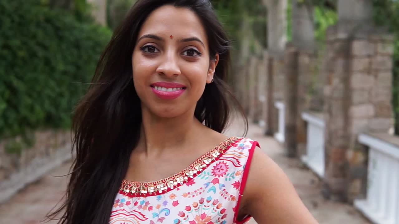 hembra india feliz girando alrededor durante un paseo en el jardín verde