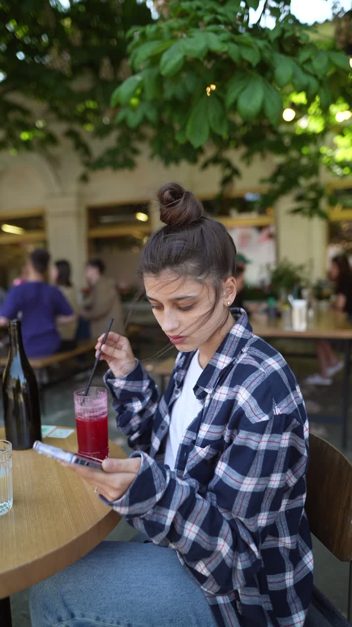 mujer usando el teléfono en un café al aire libre