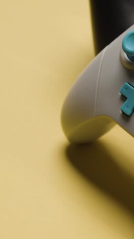 estudio de video vertical de primer plano de dos controladores de videojuegos en fondo amarillo