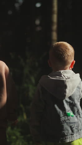 children look at dark forest at resort. thoughtful boy and girl dream about walk in night woods. little kids observe park standing on cottage pouch