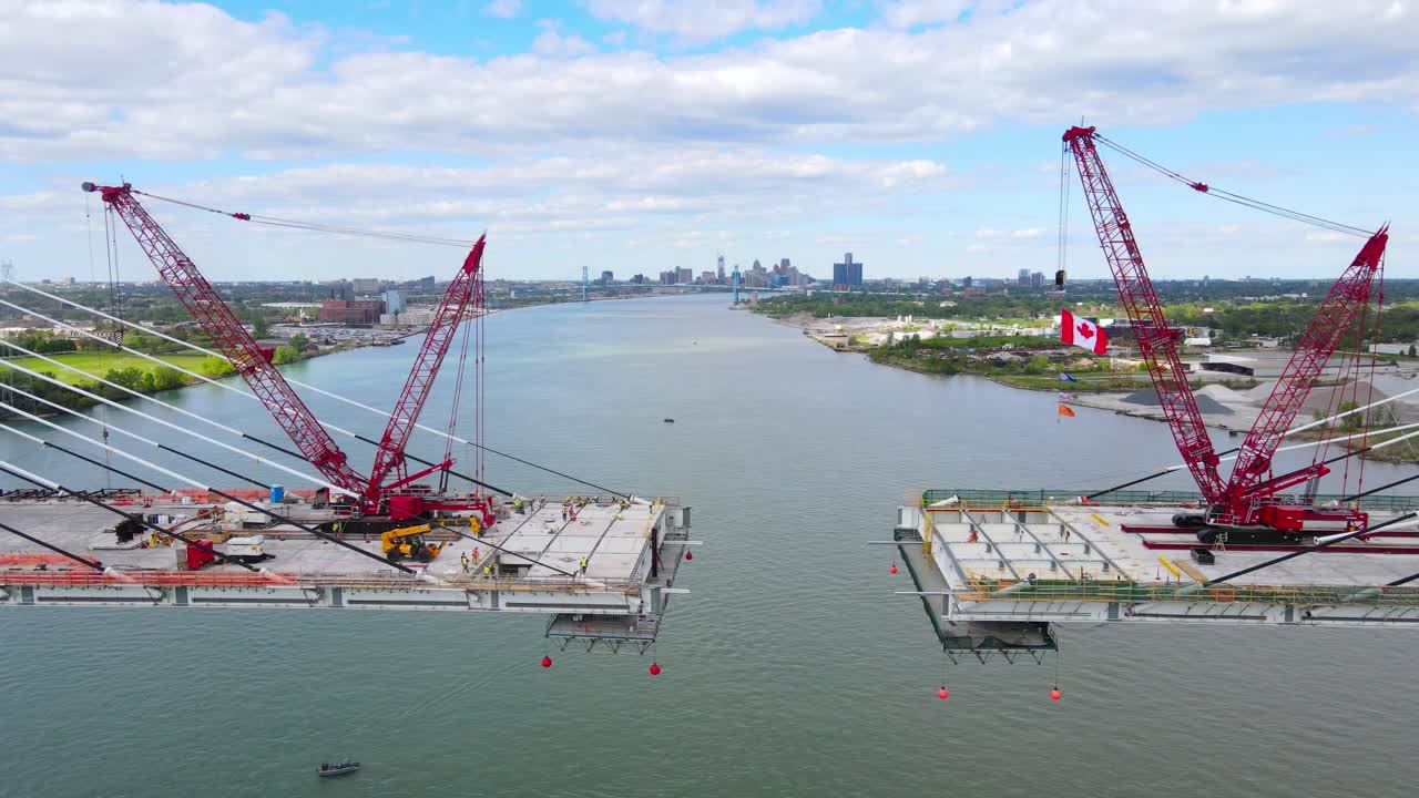 Gordie Howe international bridge construction with lattice boom crawler cranes, aerial dolly out view