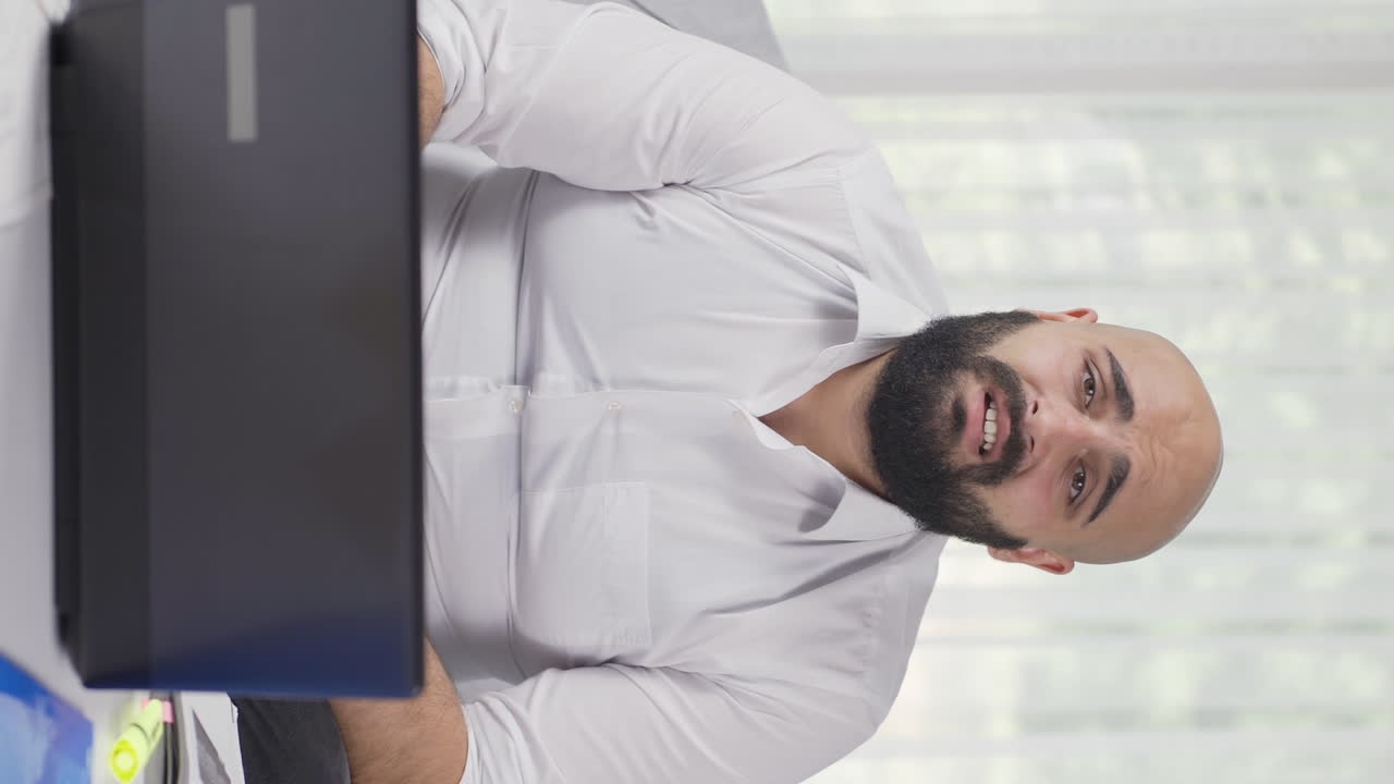 Vertical video of Home office worker man looking annoyed at camera.
