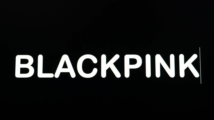Nærbillede af BLACKPINK, der tastes ind på en computerskærm med blinkende markør på sort baggrund med plads til tekst.
