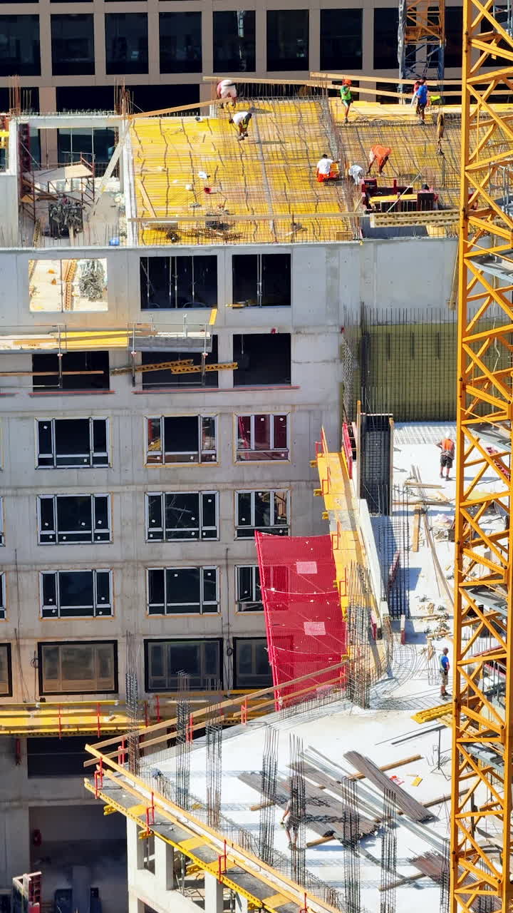 Construction site activity in urban area. Workers collaborate on a high-rise building's framework in a bustling cityscape during bright daylight hours