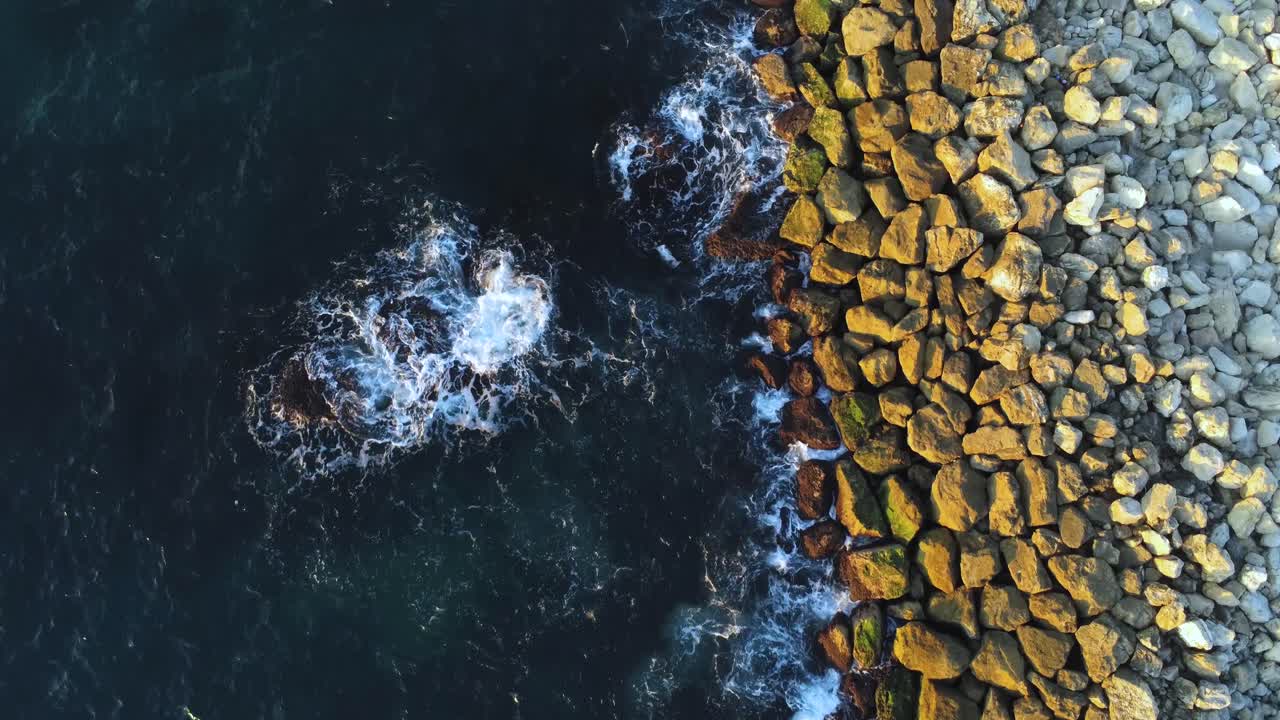 4k drone flying over the harbor breakwater looking at waves breaking on rocks