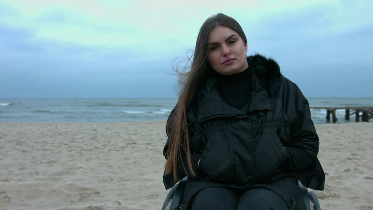Slow motion video with young disabled woman on wheelchair. First she is smiling next she is sad and depressed