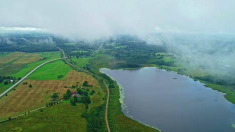 Dünne-Nebelwolken-über-Einem-Ruhigen-See,-Umgeben-Von-Einer-Grünen-Naturlandschaft