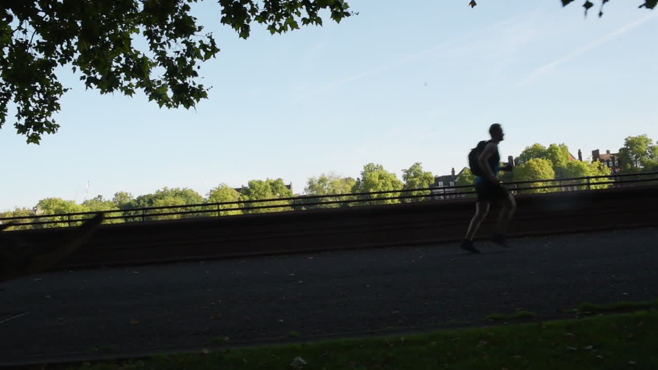 Man Exercising by Running Outdoors on Sidewalk Path - Silhouette Tracking Motion