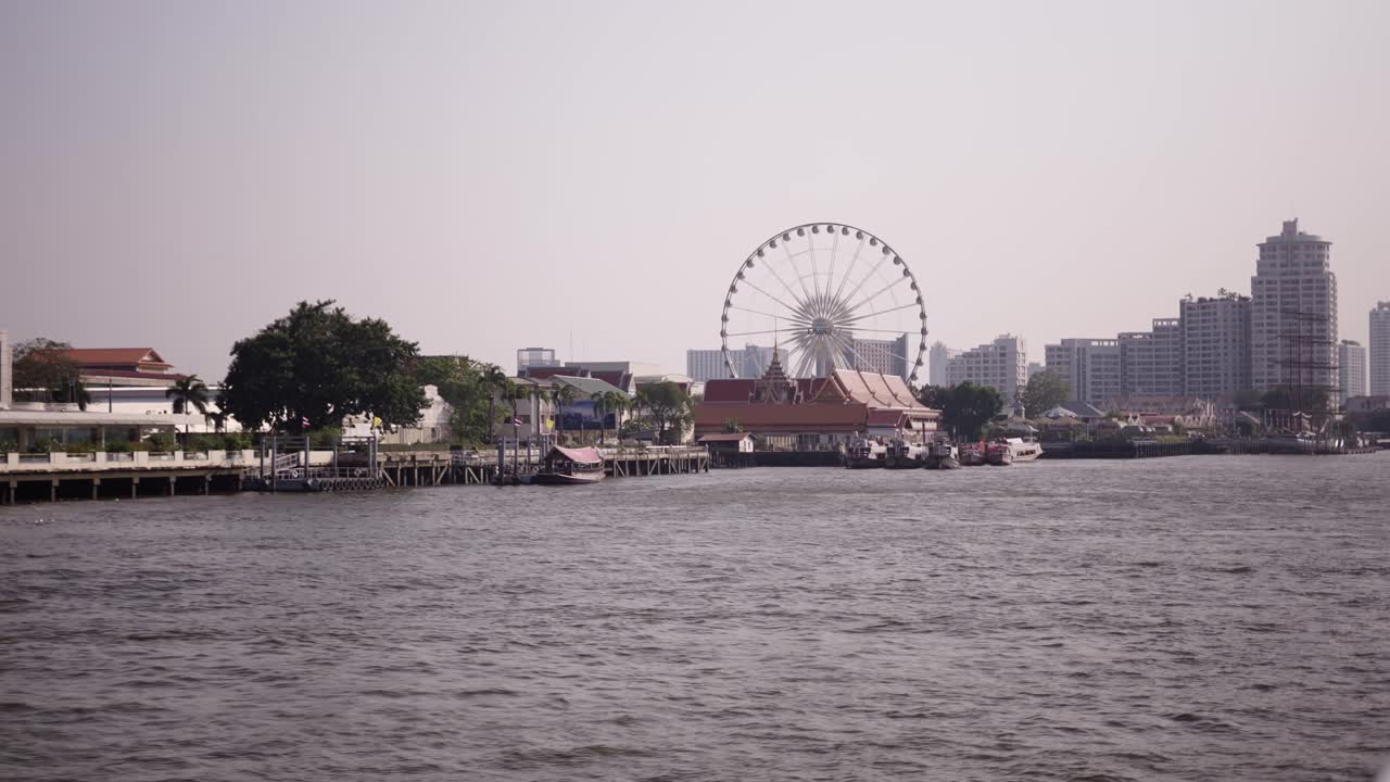 Riverfront view in Bangkok with Ferris wheel and temples
