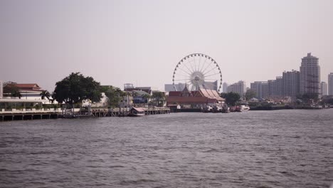 riverfront view in bangkok with ferris wheel and temples