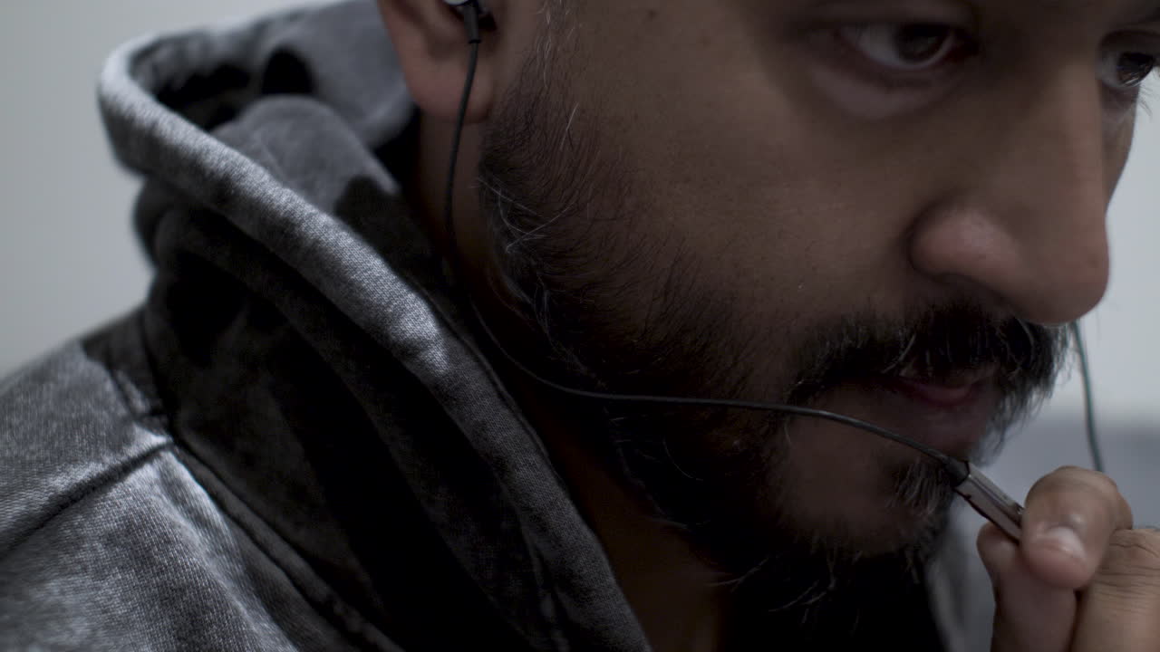 Close up shot of the face of an Indian man talking into the microphone of his earphone headset during a telephone call