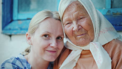 Portrait-Of-An-Elderly-Woman-With-Her-Granddaughter-They-Embrace-They-Look-At-The-Camera-A-Few-Gener