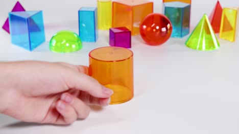 hands interact with colorful 3d geometric shapes on a white surface, highlighting educational and playful exploration