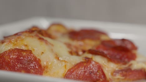 a close up of pizza slices on a plate, showcasing their melty cheese and rich toppings