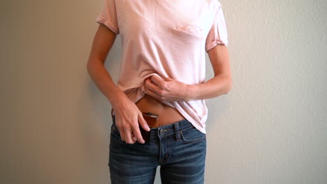 slow motion of a woman puling up her shirt and removing her concealed and holster gun from her waistline