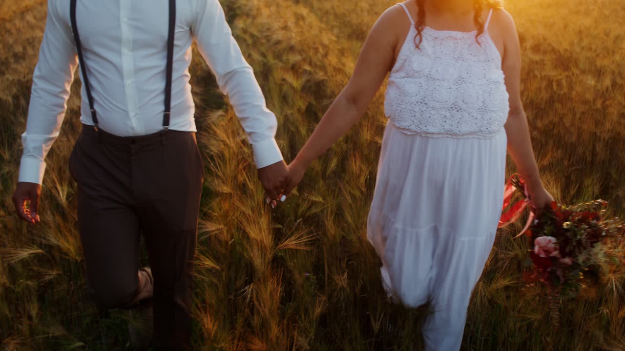 una pareja besándose y caminando en un campo de trigo al atardecer