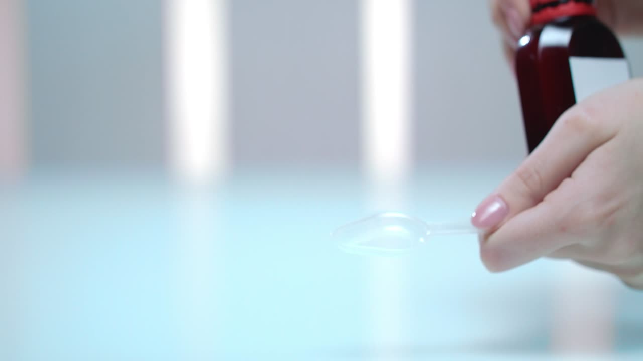 여성이 병에서 약 시럽을  ⁇ 고 있습니다. 독감 예방, 건강 관리