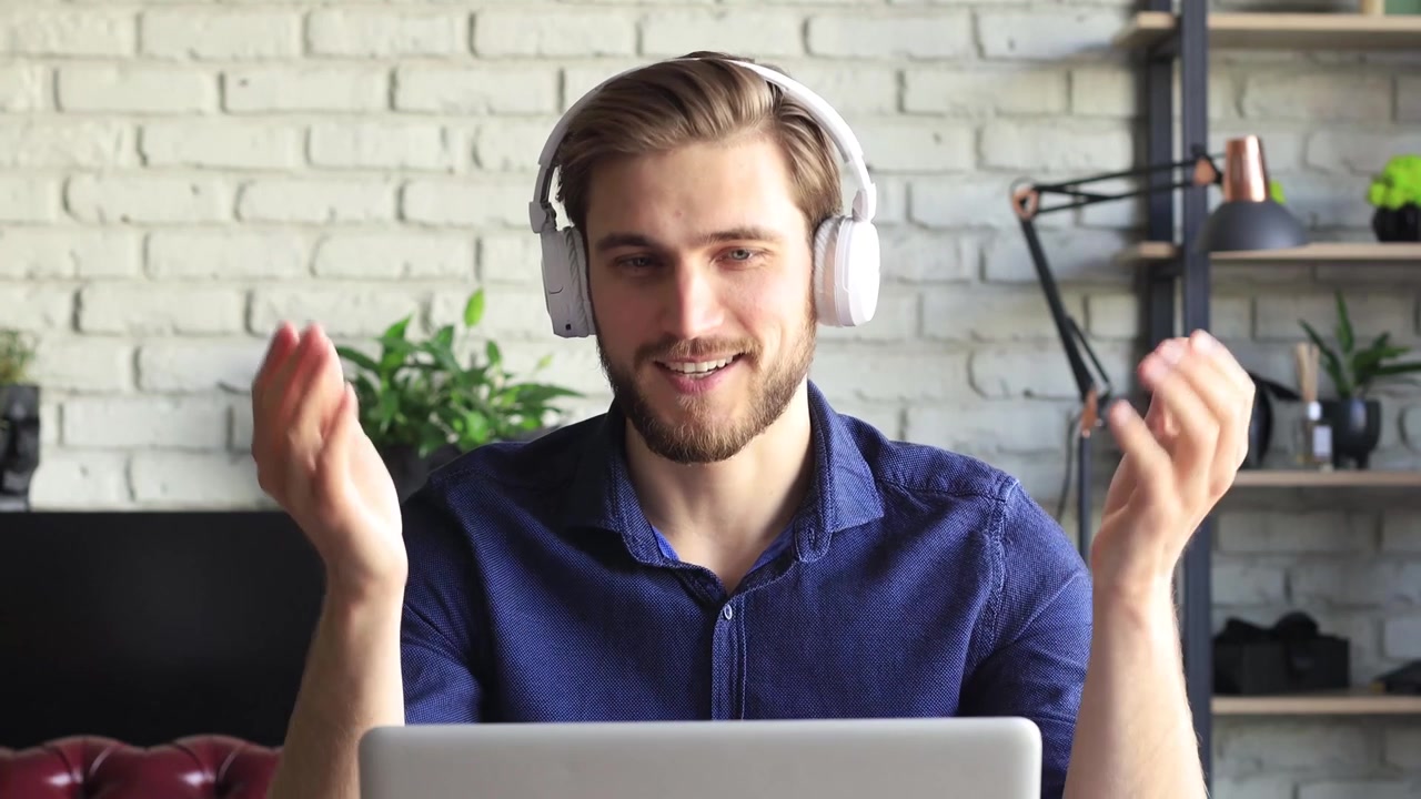 Young Man in Headphones Talking and Gesturing During Video Call