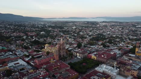 Luftparallaxe-Der-Majestätischen-Kirche-Parroquia-De-San-Miguel-Arcángel-In-San-Miguel-De-Allende-Während-Einer-Reise-Durch-Mexiko-Mit-Einer-Malerischen,-Farbenfrohen-Stadtlandschaft-Mit-Historischen-Gebäuden-An-Einem-Sonnigen-Abend