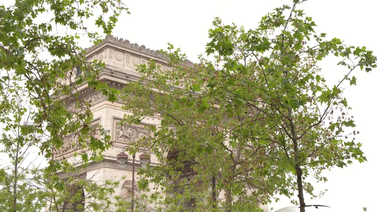 Inquadratura statica dell'Arco di Trionfo attraverso il fogliame verde sotto la luce del sole brillante a Parigi.