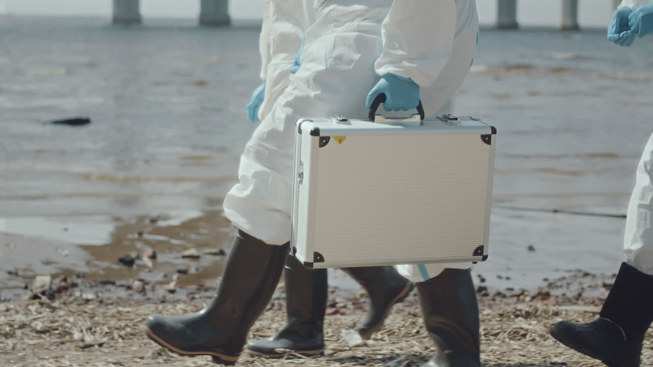 Group of Ecologists in Coveralls Walking along Shore