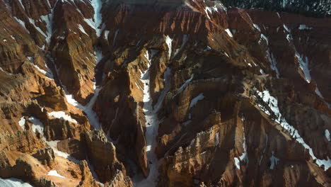 Aerial-view-panning-above-snowy,-red-rock-formations,-in-sunny-Bryce-Canyon,-USA