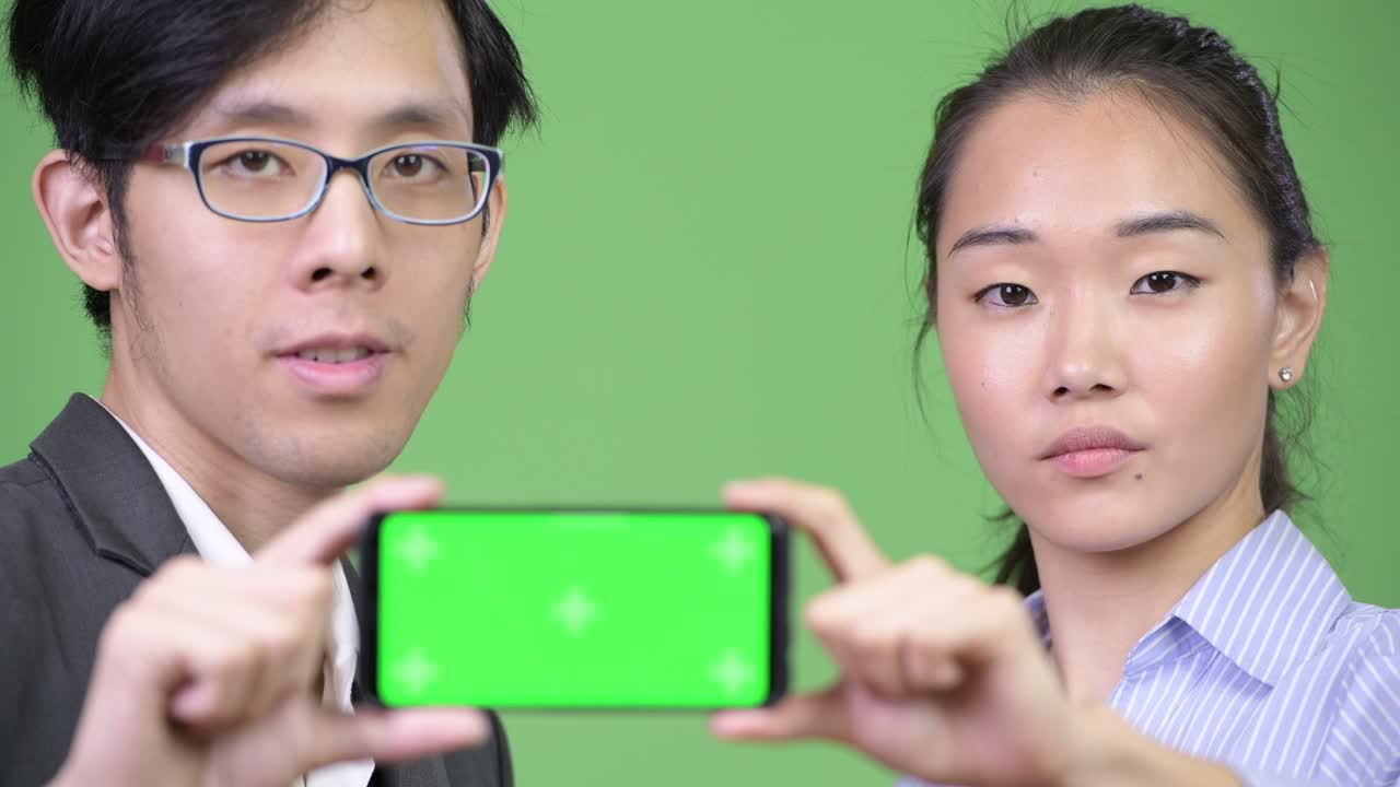 Young Asian business couple showing phone together