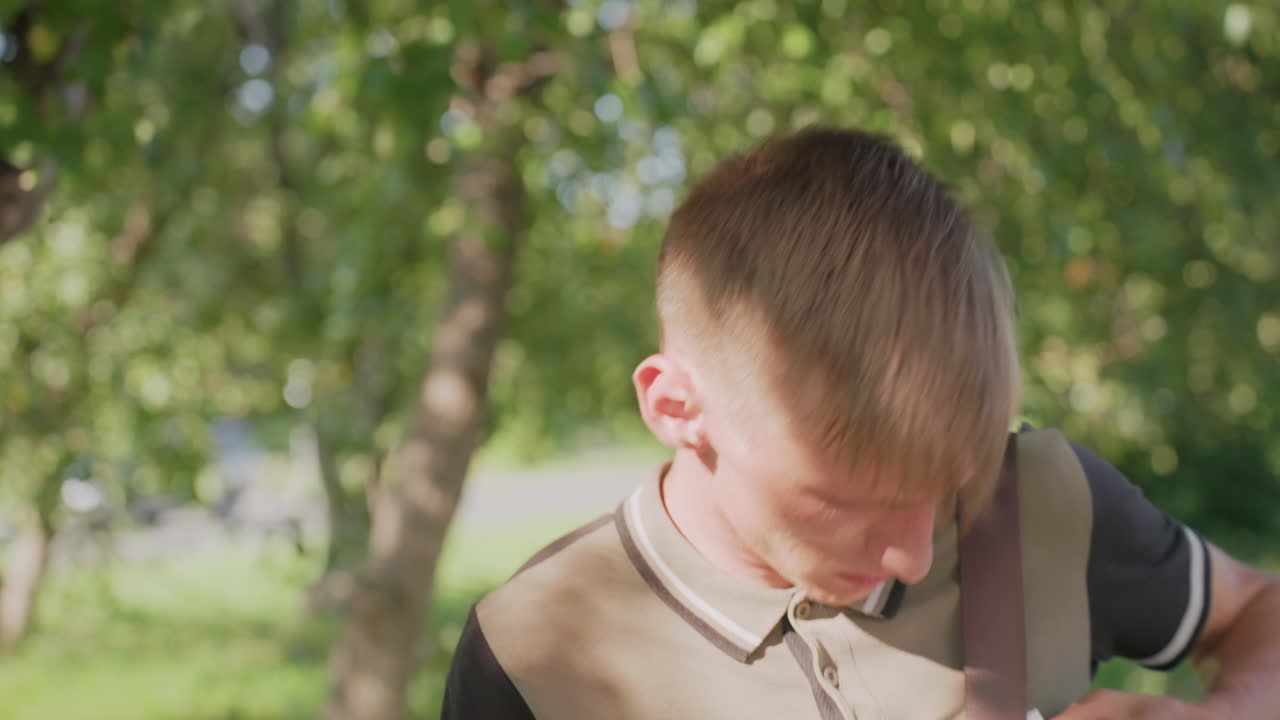 Youth Disinfects Hands, Young Man Sanitizes Carefully Outdoors, Man Uses Sanitizer Thoughtfully In Park Environment, Youth Applies Disinfectant With Delicate Hand Gestures Amidst Shaded Park Scene