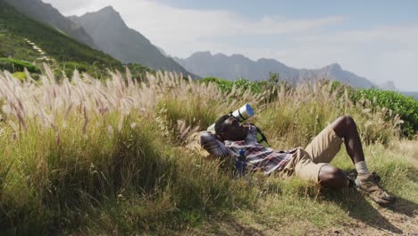 african american man lying on a rock while trekking in the mountains