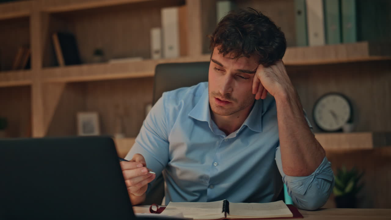Tired student video calling by laptop in dark apartment closeup. Unmotivated man