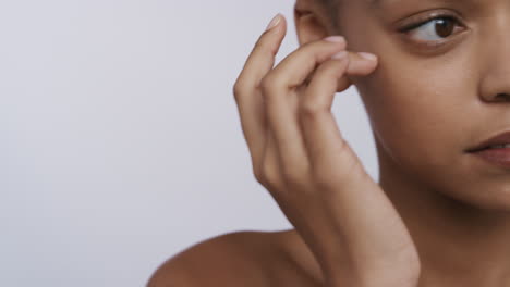 de cerca hermosa mujer afroamericana tocando la cara con las manos acariciando piel suave y saludable disfrutando de un tratamiento natural de cuidado de la piel sobre un fondo blanco concepto de belleza