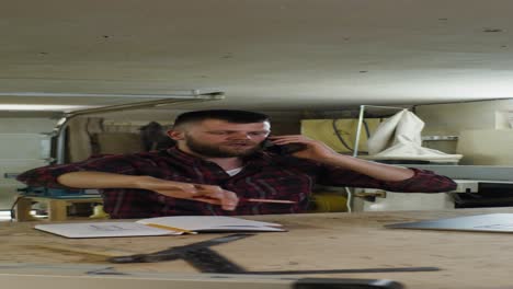 man talking on phone while working in a workshop