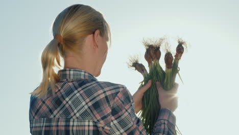 back view of a female farmer with a green onion in her hands organic farming concept