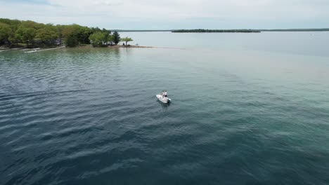 A-fishing-boat-trolls-the-edge-of-the-drop-off-at-Detroit-Point-on-Higgins-Lake,-Roscommon,-MI