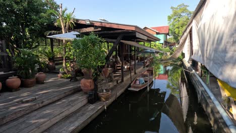 boat approaches a wooden dock by a tropical house.