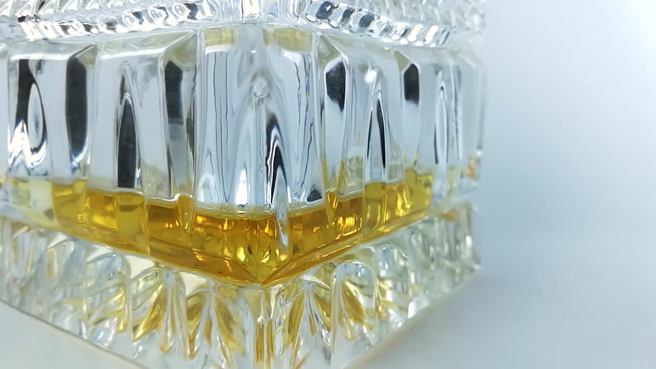 Bottom of a beautiful crystal bottle with a little whiskey in it on a white background