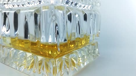bottom of a beautiful crystal bottle with a little whiskey in it on a white background