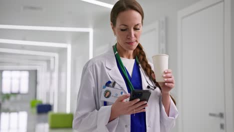 médico usando un teléfono inteligente en un pasillo del hospital