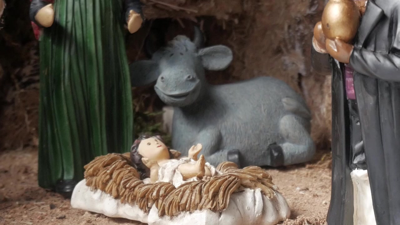 A close-up shot focuses on the baby Jesus figurine in the manger, flanked by a calf, one of the kings, and Mary. This beautifully crafted scene captures the essence of Christmas.
