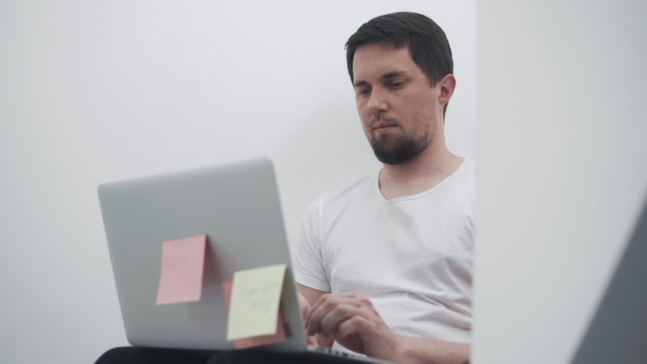 joven empleado de oficina se sienta frente a una computadora portátil y está desarrollando un proyecto de inicio