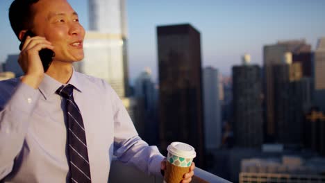 asian american businessman speaking on smartphone on rooftop