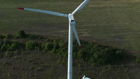 aerial drone shot around single wind turbine generator in grass field-1