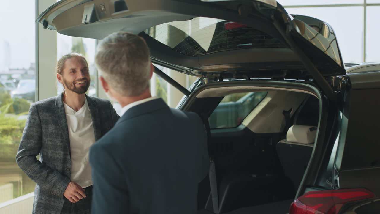 vendedor de automóviles mostrando el maletero de un vehículo a un cliente